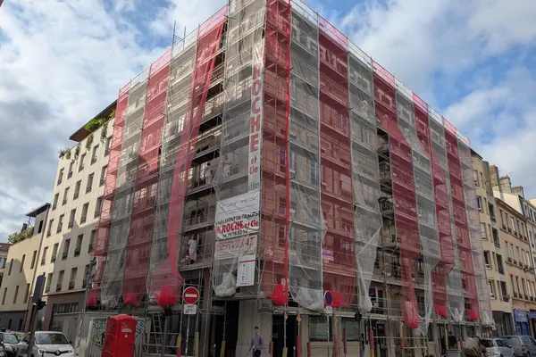Immeuble sous échafaudage et filets pendant un ravalement de façade, dans le 7e arrondissement de Lyon